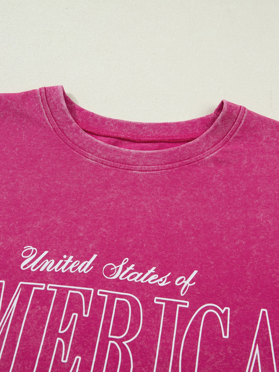 Patriotic graphic cotton t-shirt in faded pink with white "United States of America" text.