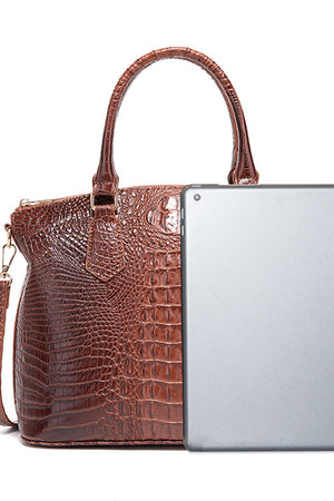 Brown crocodile embossed satchel bag with top handle and shoulder strap, shown with a tablet for scale.