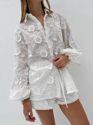 White embroidered two-piece shirt and shorts set with floral applique and button-down closure.