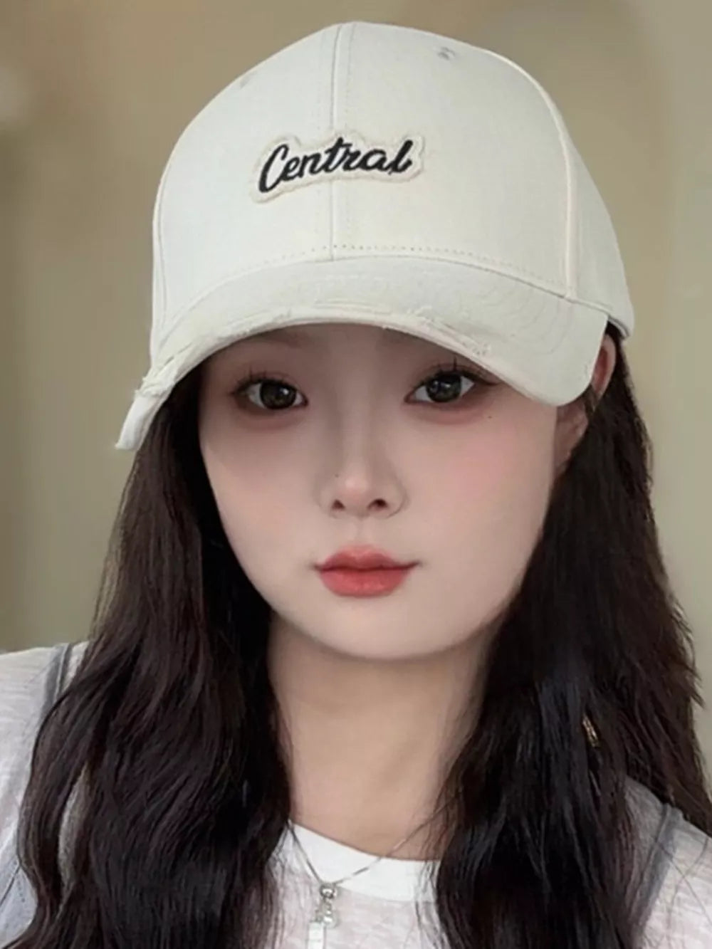 Cream baseball cap with embroidered Central logo and distressed brim.