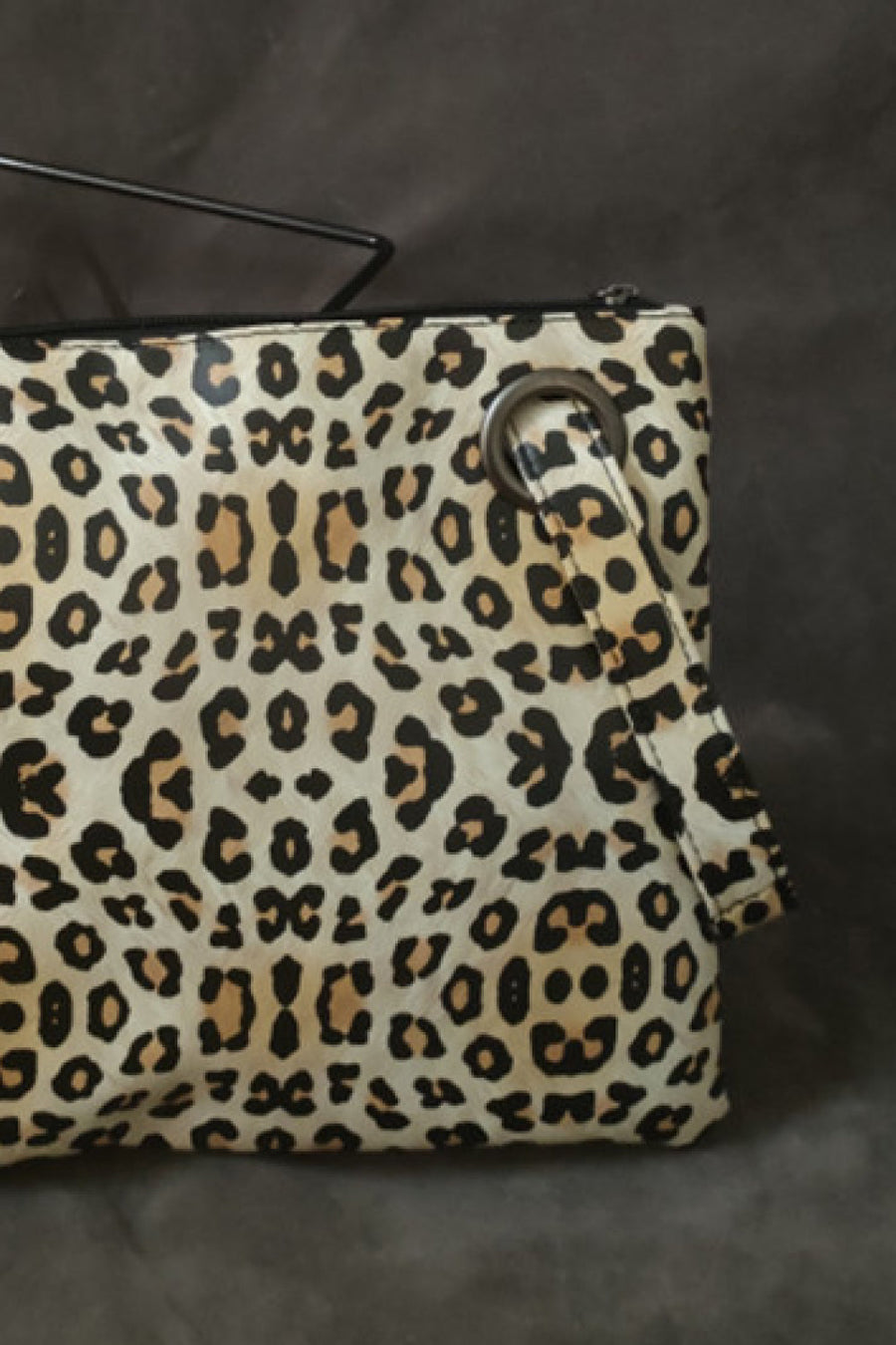 Leopard print zip-top clutch with a metal ring detail and wrist strap.
