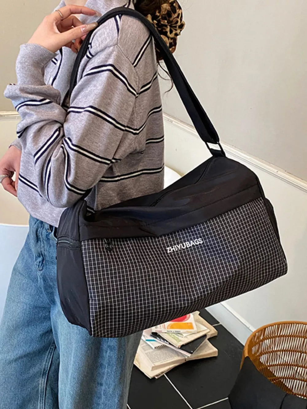Black travel organizer bag with plaid detail and white text logo.