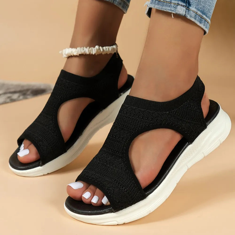 Black knit peep-toe sandals with white soles and a cutout detail.