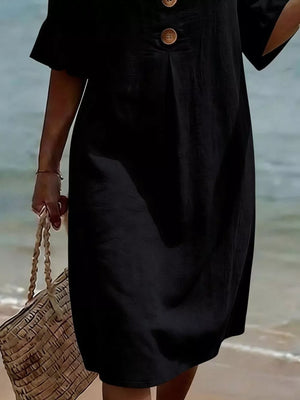 Black casual dress with ruffled sleeves and button detail, styled with a straw bag.