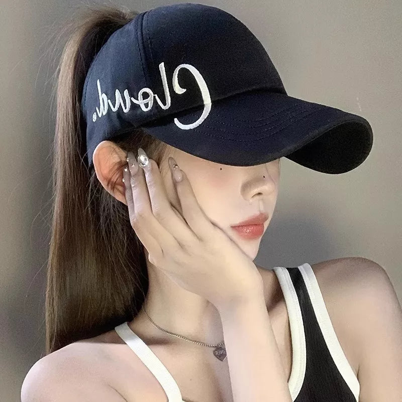 Black baseball cap with white embroidered text, adjustable strap, and ponytail hole.