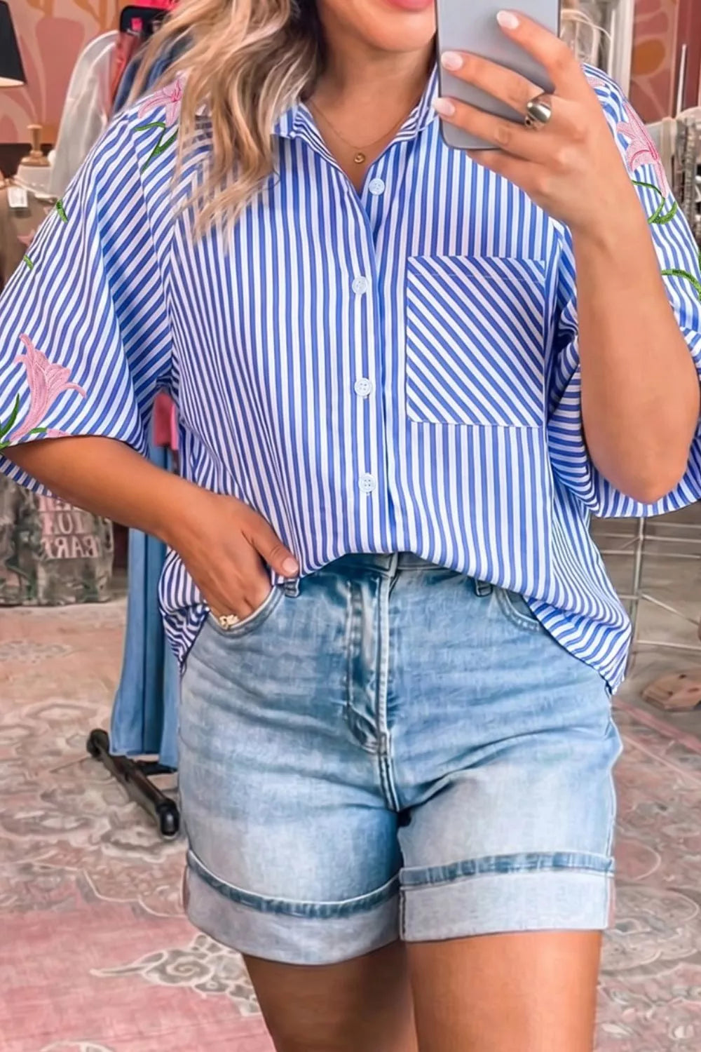 Blue and white striped button-down shirt with floral embroidery on sleeves and pocket.