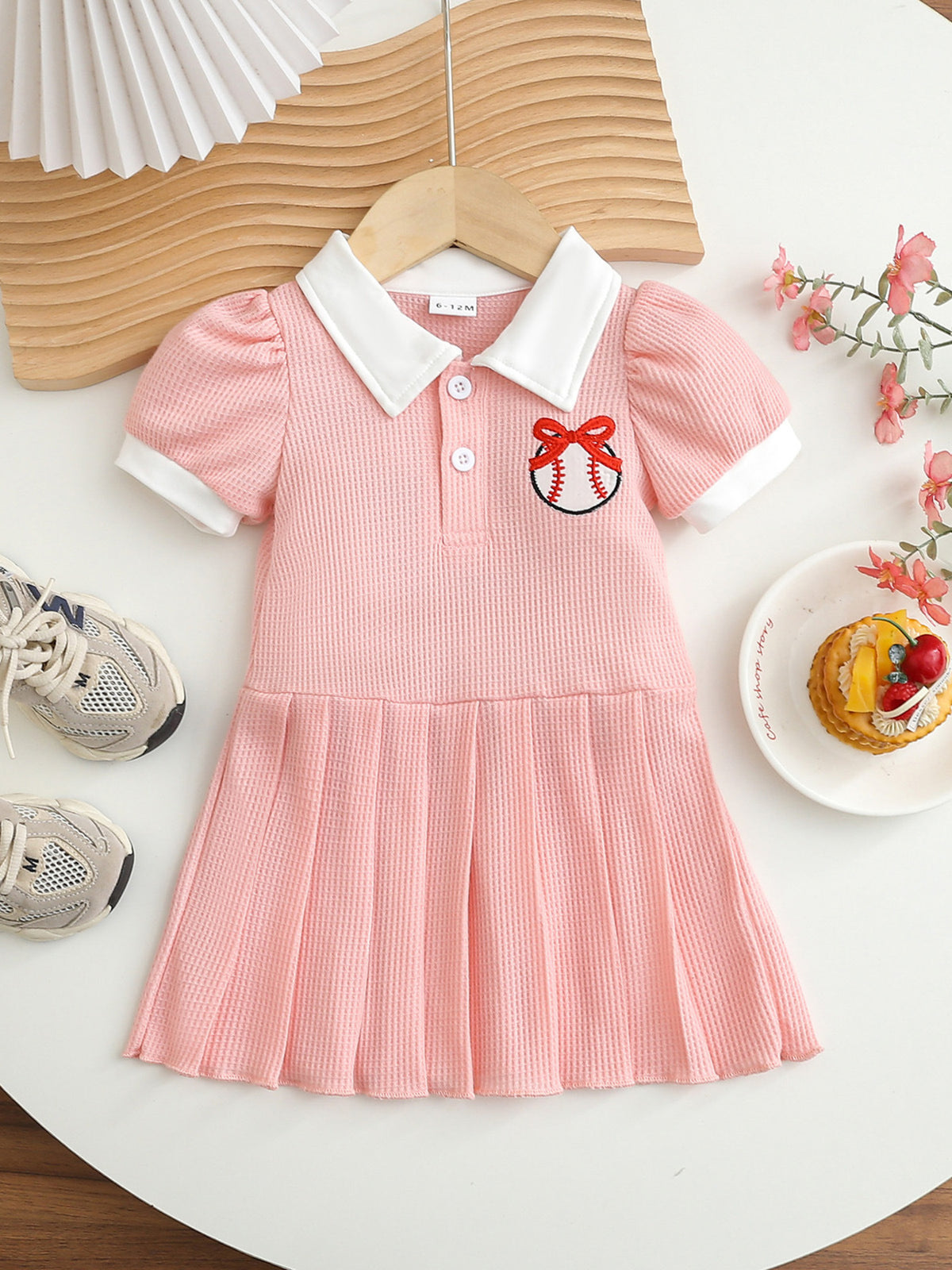 Pink baby dress with white collar, short sleeves, and baseball embroidery.