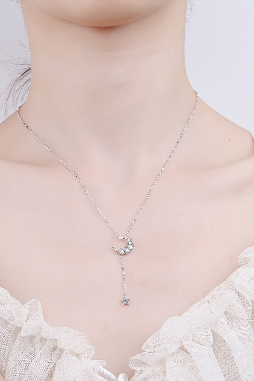 Silver celestial pendant necklace with crescent moon and star charms.