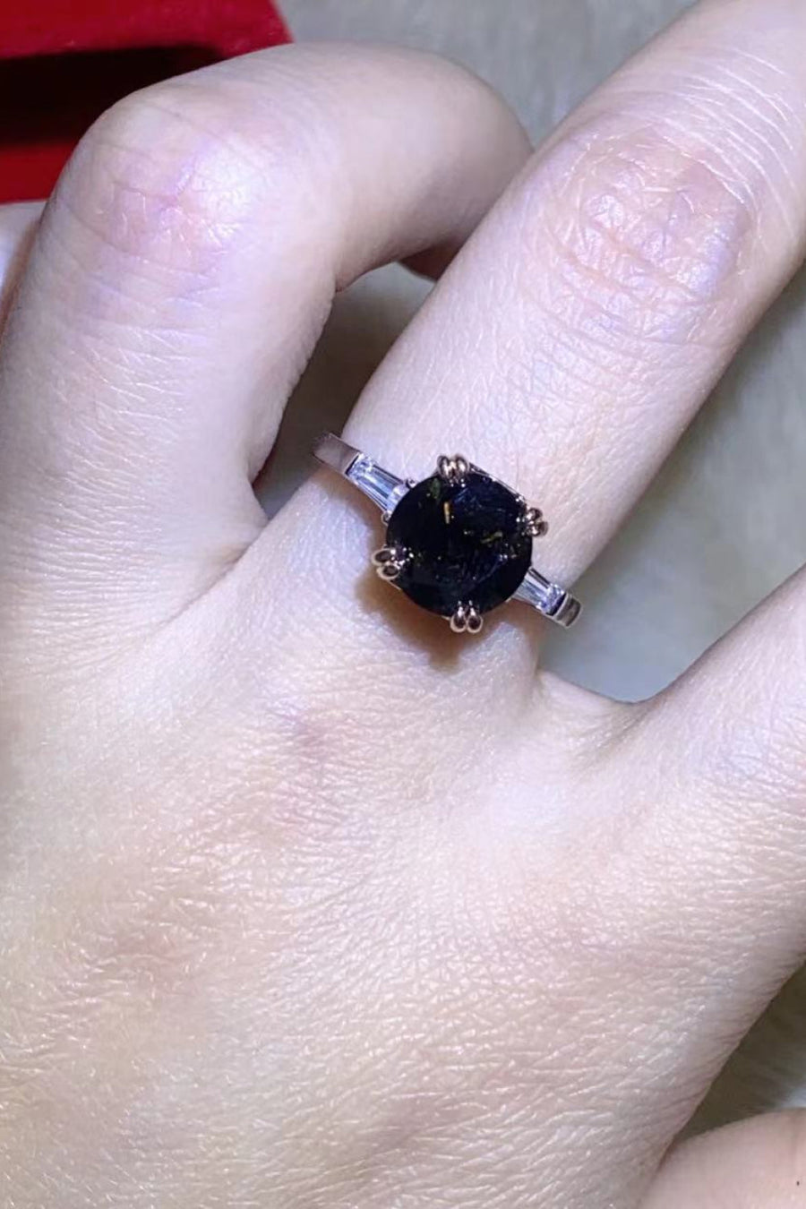 Black moissanite solitaire ring with baguette accents on a silver band.
