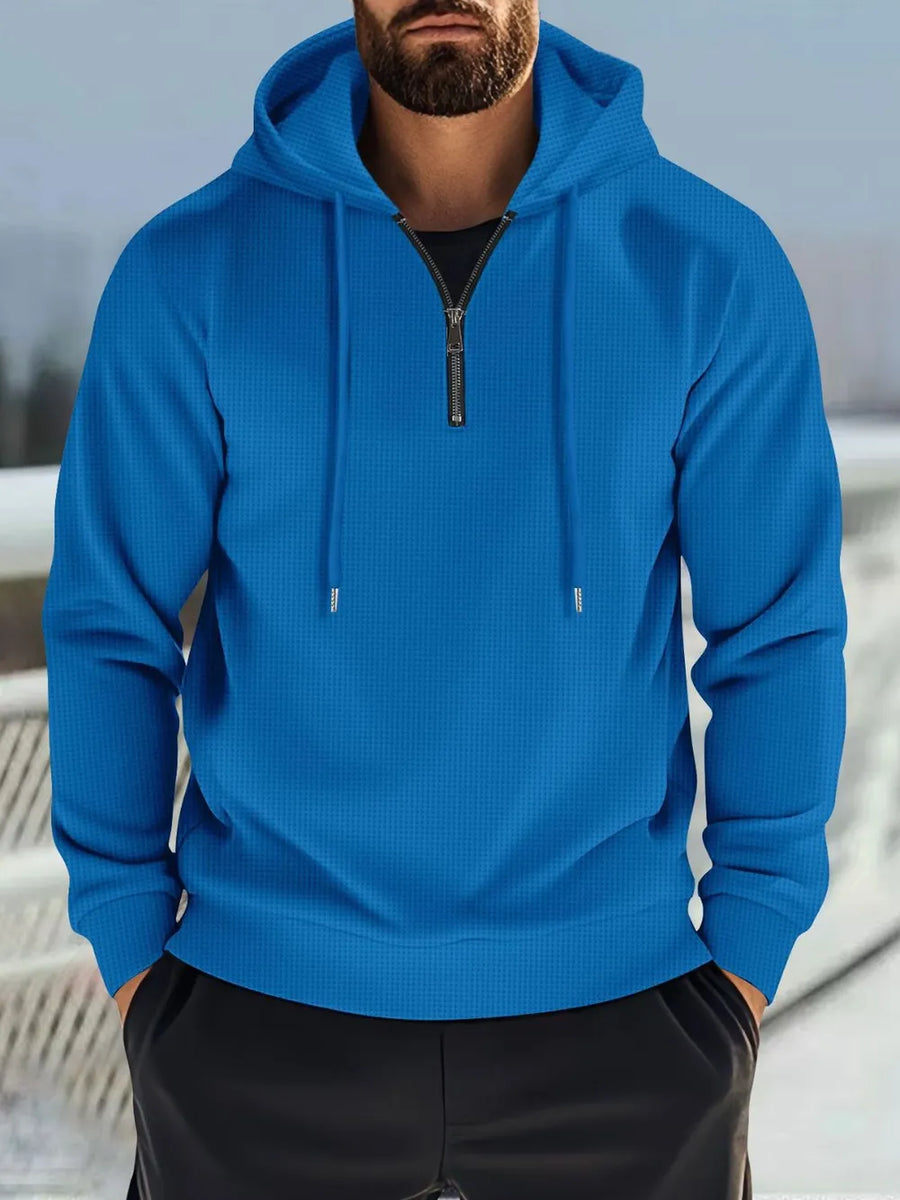 Blue waffle-knit quarter-zip hooded pullover with drawstring hood and black t-shirt.