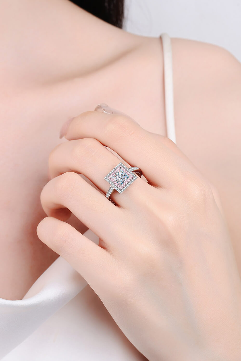 Princess cut halo ring in silver with pink accents and a diamond band.