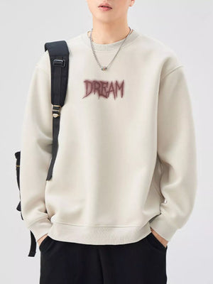 Oversized crew-neck sweatshirt in a light beige with a dark red "DREAM" graphic.