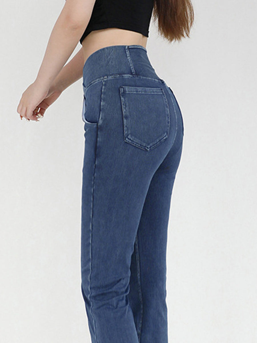 Medium wash denim jeans with crossover waist and flare leg, detailed view of back pockets.