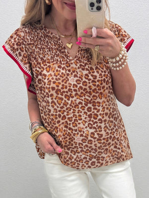 Smocked ruffled print blouse with animal print, V-neck, and red trim sleeves.