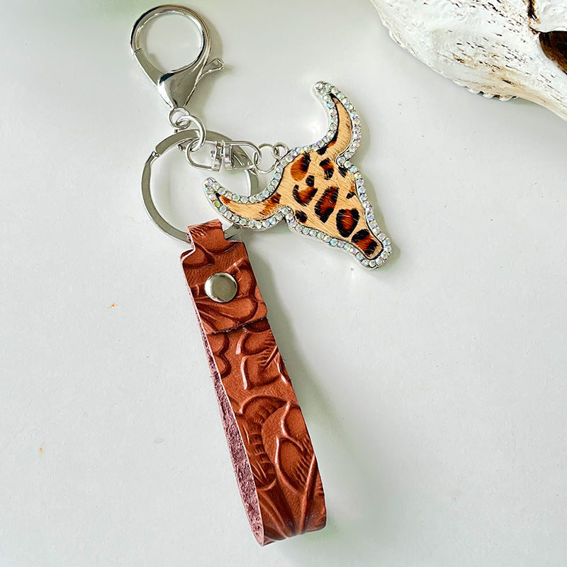 Western keychain with bull skull, leopard print, crystals, and embossed leather strap.