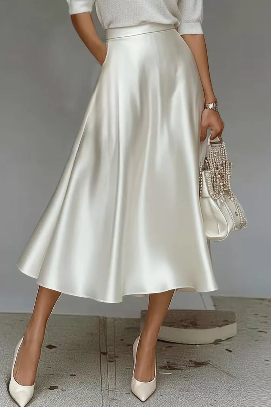 White midi a-line skirt with hidden pockets, made of lustrous satin fabric.