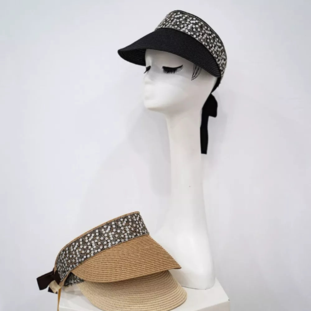 Sparkling straw visor hat with ribbon tie in black and beige, featuring decorative band.