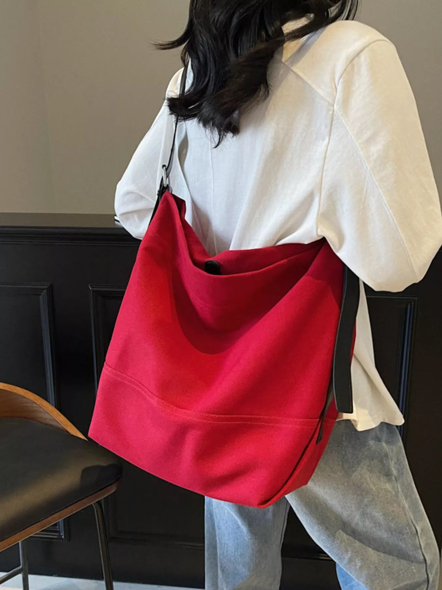 Red hobo bag with adjustable strap, casual style, worn over the shoulder.
