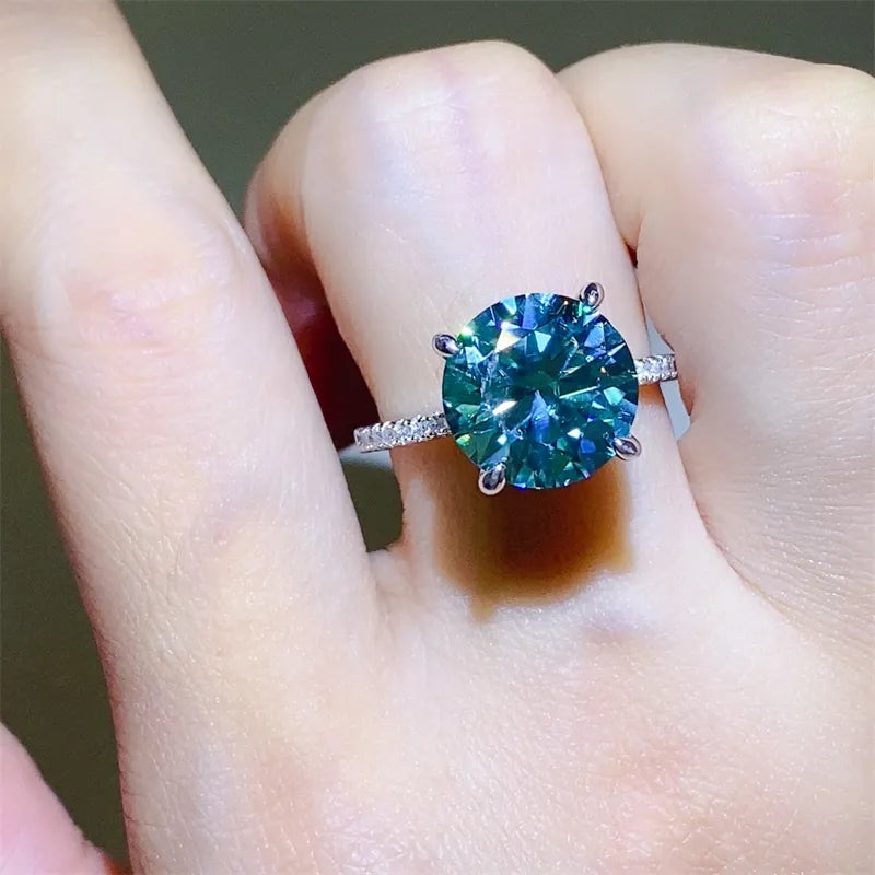 Radiant teal moissanite pavé ring in silver with a large round-cut center stone.