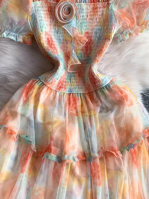 Floral tiered midi dress with smocked bodice and sheer sleeves in a pastel tie-dye print.