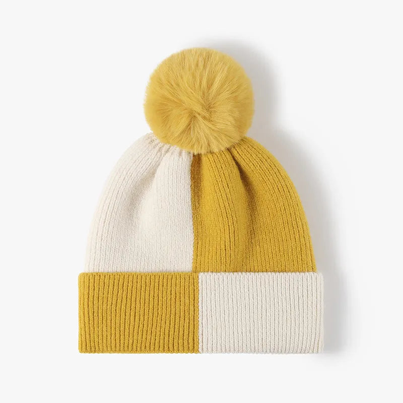 Colorblock knit beanie with yellow pom and checkerboard pattern in yellow and cream.