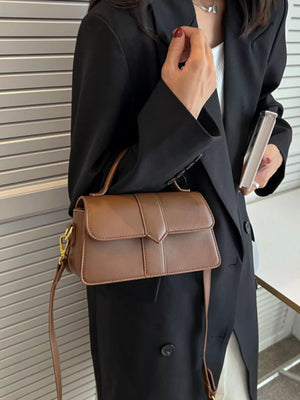 Brown leather top handle shoulder bag with flap closure and gold hardware.