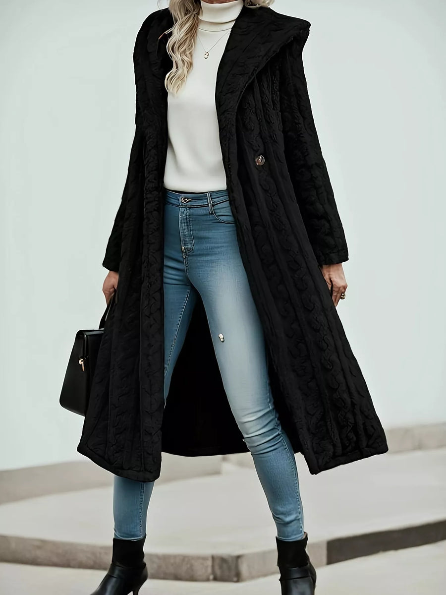 Black hooded longline button up outerwear with textured pattern, worn open over jeans and a turtleneck.