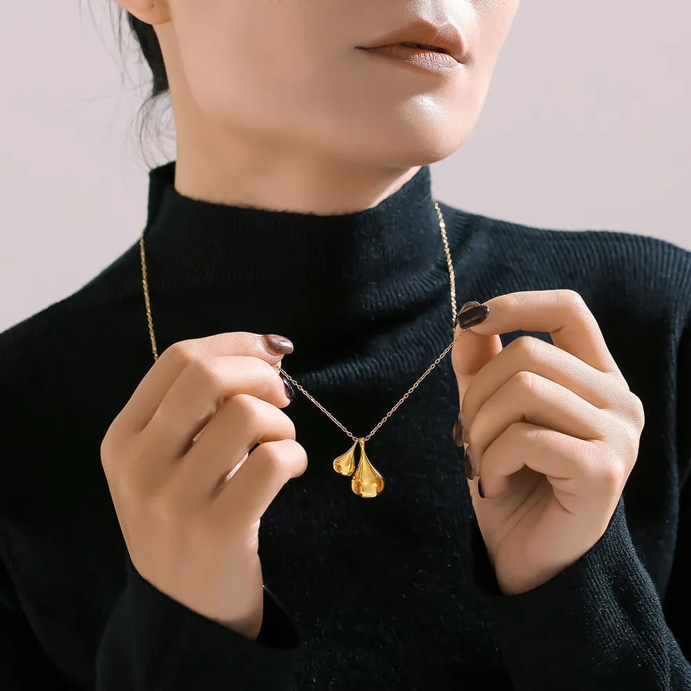 Gold pendant necklace with two sculptural leaf-shaped charms on a delicate chain.