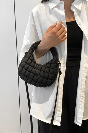 Black padded crescent crossbody bag with sculptural texture and a top handle.
