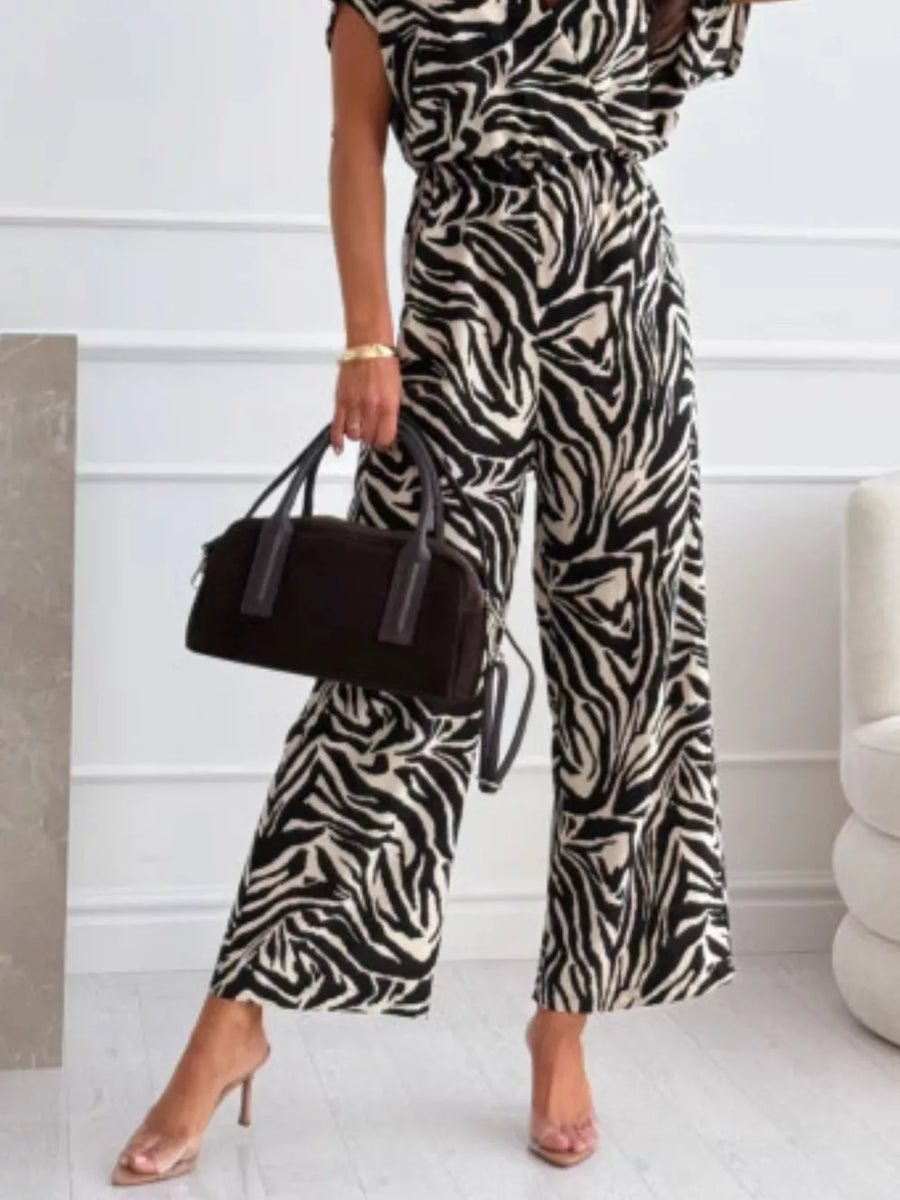 Chic zebra print wide-leg romper with cap sleeves and a cinched waist.