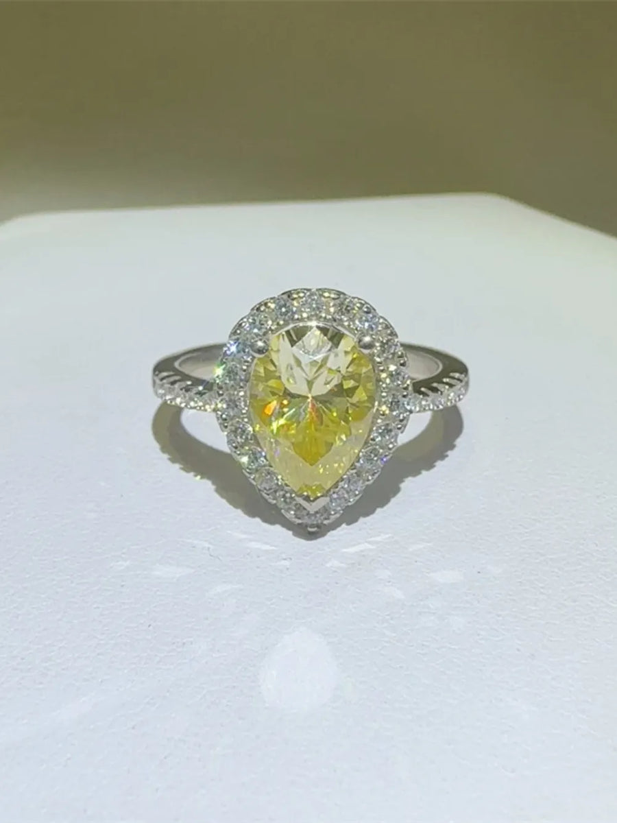 Yellow pear-cut moissanite ring with diamond halo and textured band.