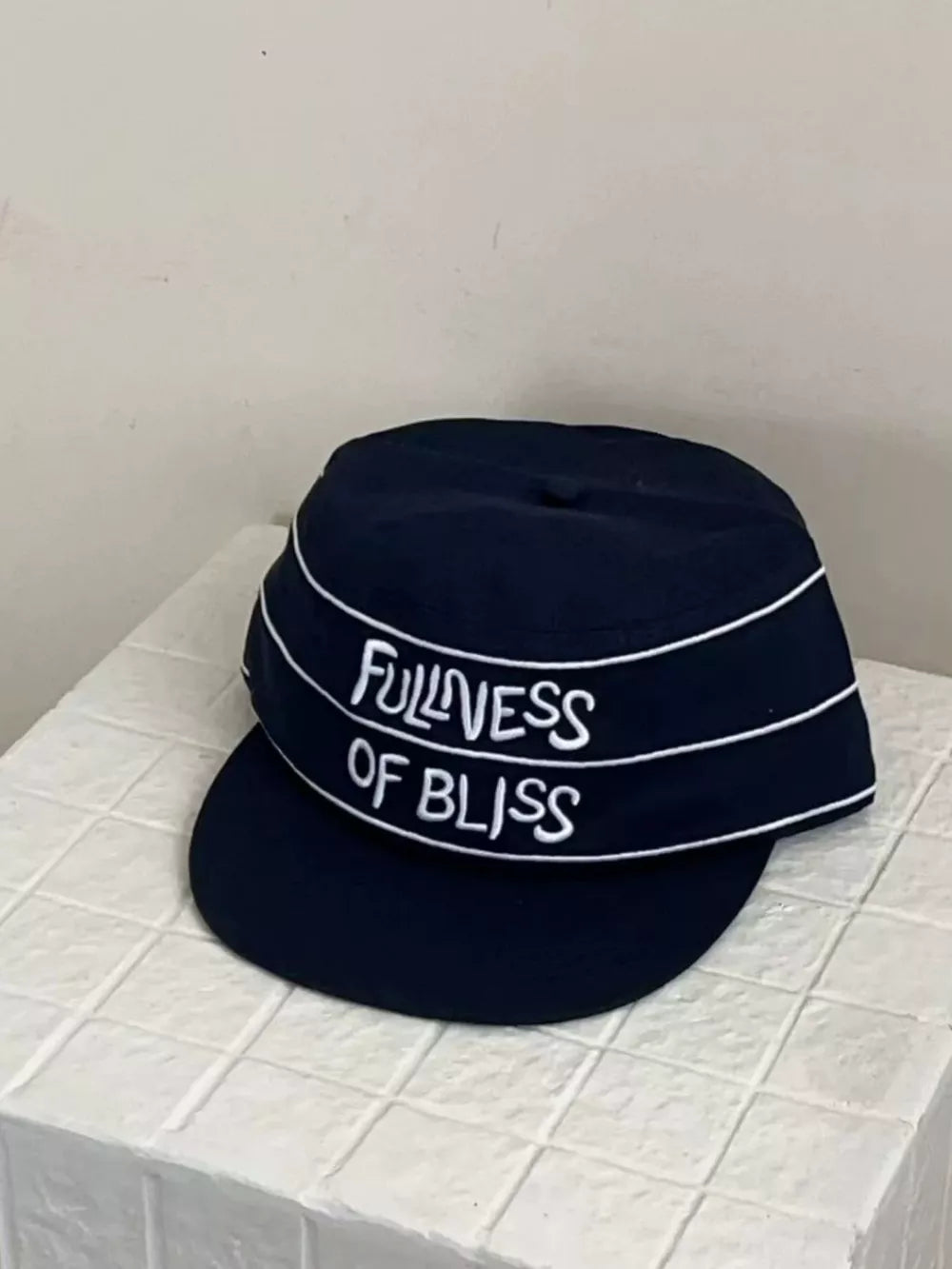 Navy blue cotton baseball cap with white embroidered slogan Fullness of Bliss and trim.