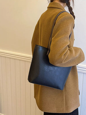 Black PU leather shoulder tote bag with a textured finish, worn by a woman.