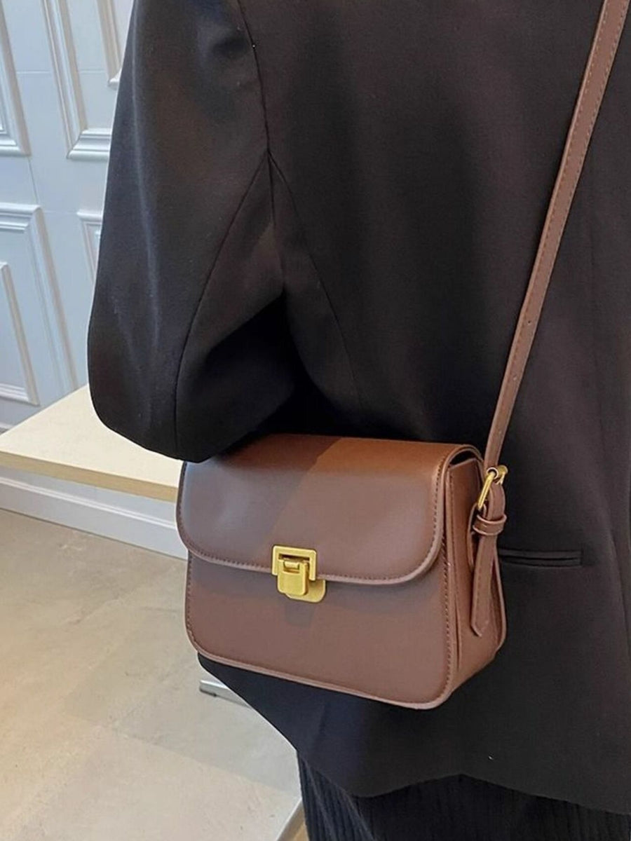 Brown leather shoulder bag with gold buckle flap closure and adjustable strap.