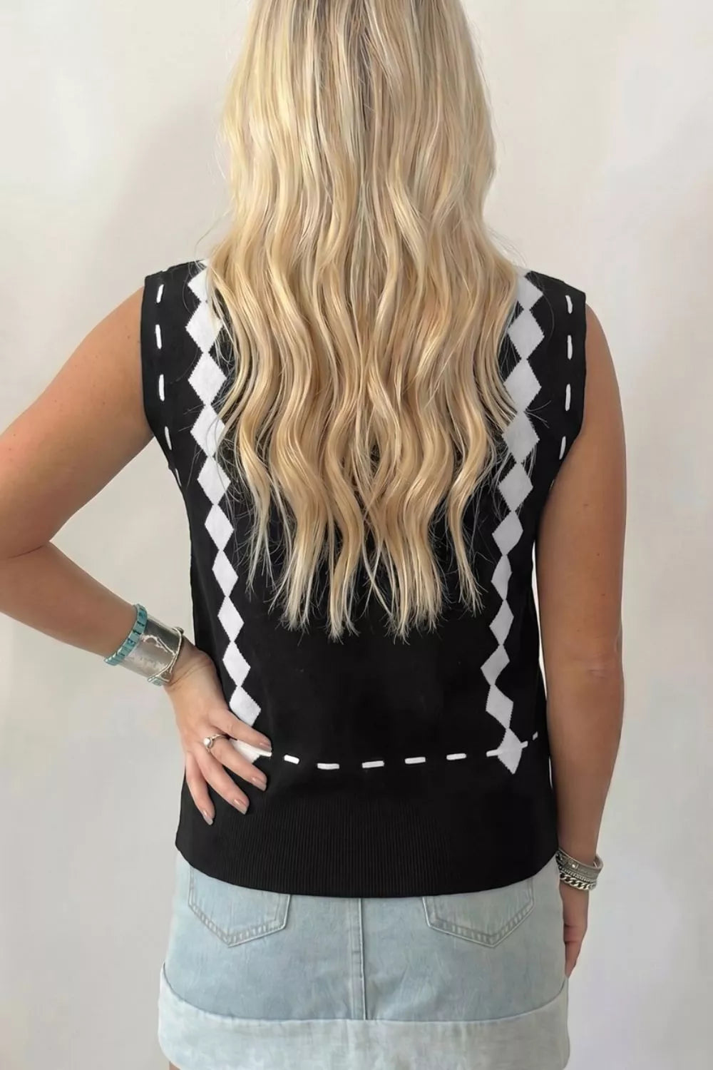Black mock neck sweater vest with white diamond pattern and dashed line detail.