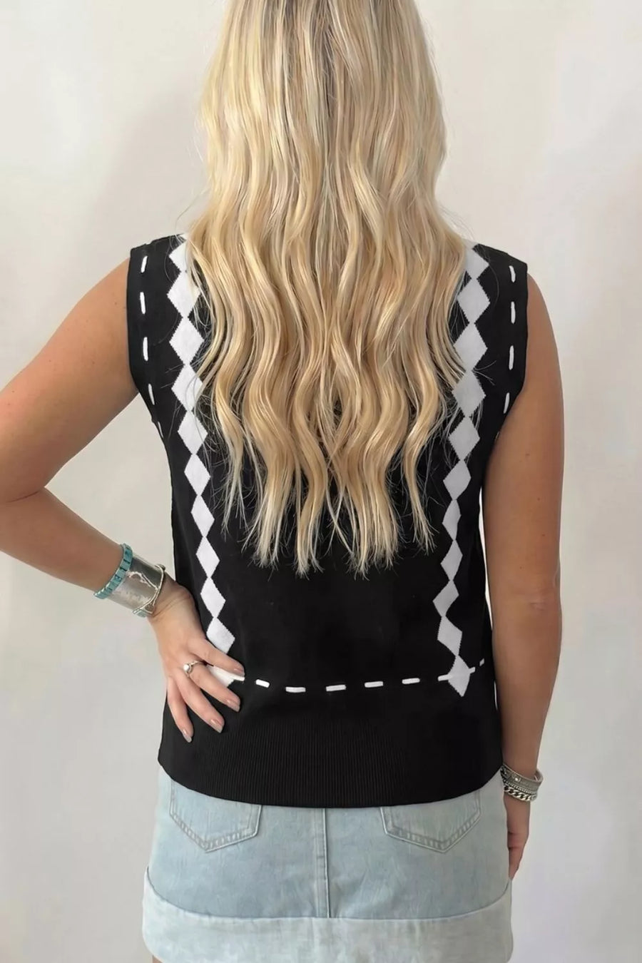 Black mock neck sweater vest with white diamond pattern and dashed line detail.
