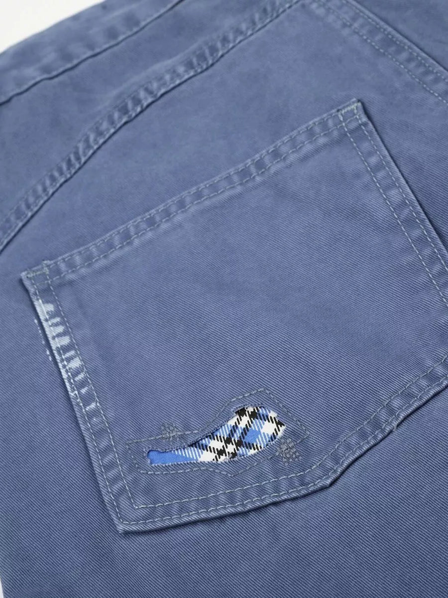 Blue faded cargo capris with distressed detailing and plaid pocket accent.