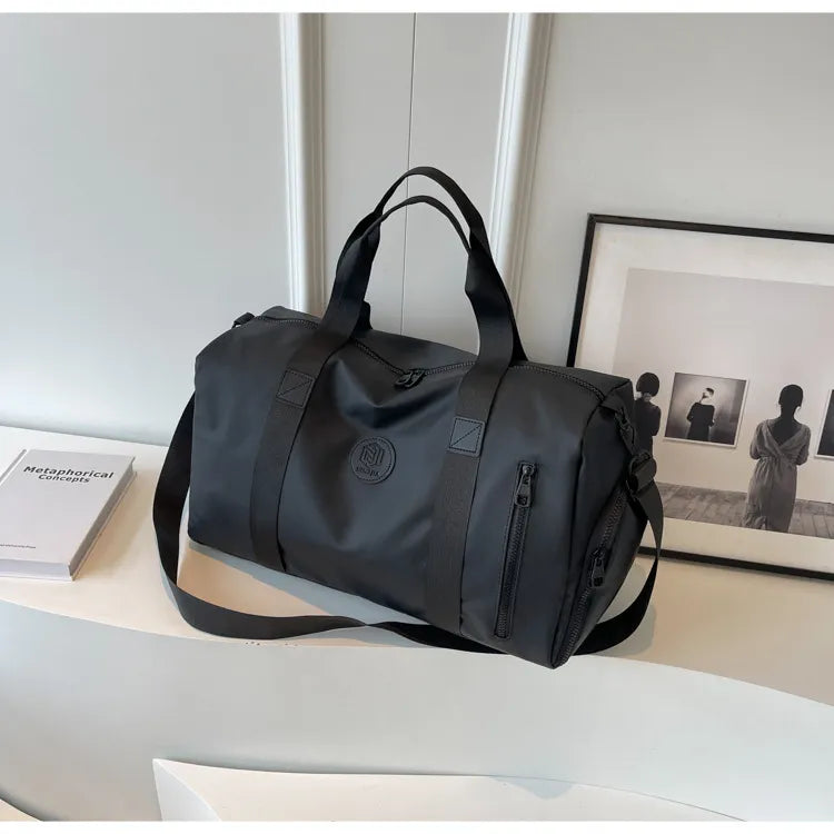 Black canvas duffel bag with contrast straps and zippered pockets.