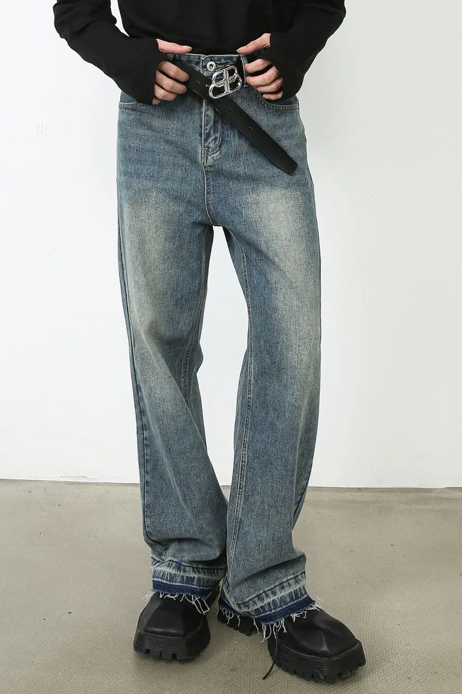 Distressed wide-leg denim jeans in medium wash with raw hem and a black belt.