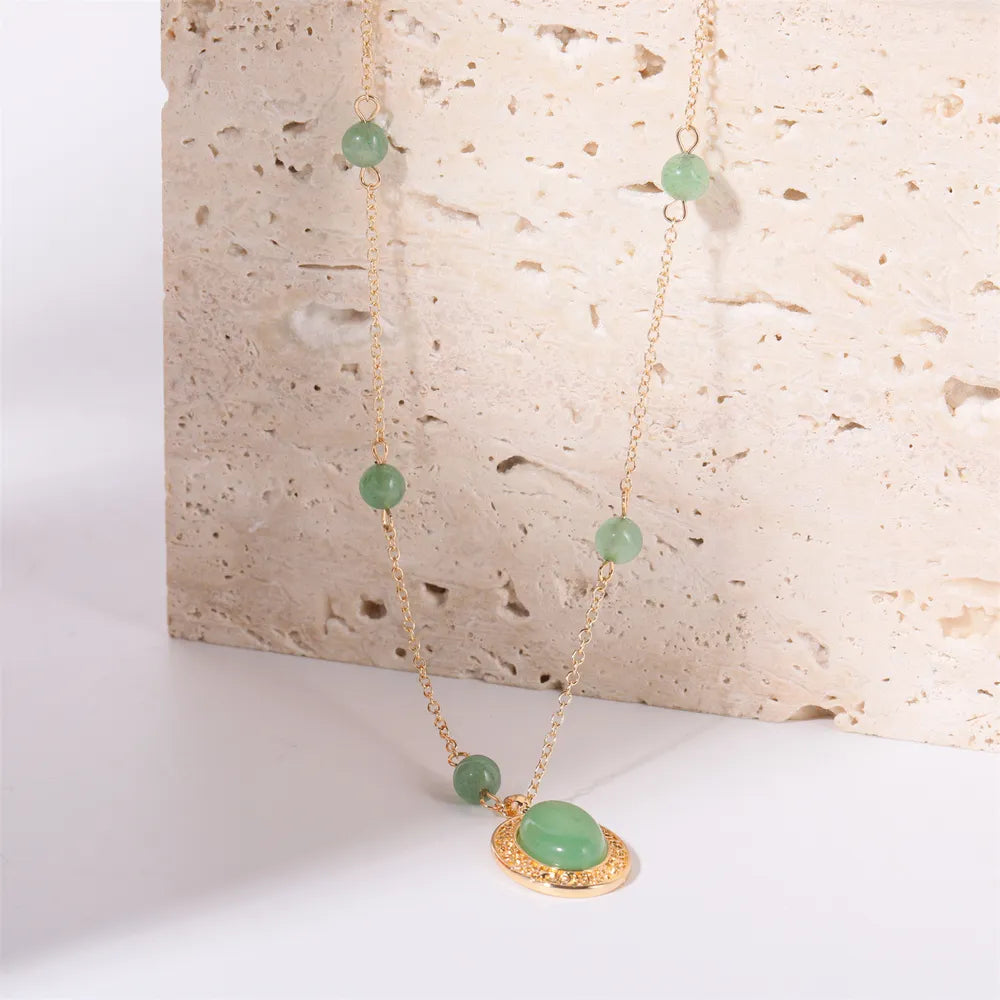 Gold chain necklace with neon green jade orb pendant and beaded accents.