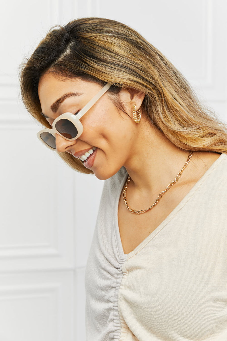Cream tortoiseshell oval sunglasses with sunset lenses and a ruched cream top.