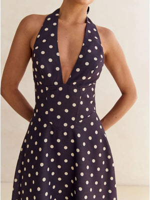 Navy polka dot halter neck maxi dress with a deep V-neck and A-line skirt.