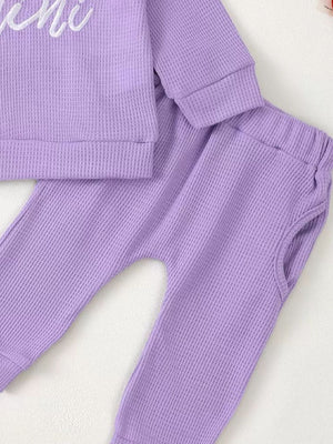 Toddler purple waffle knit top and pants set with ruffled trim detail.