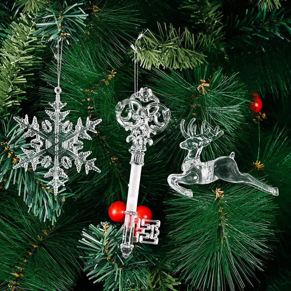 Clear snowflake, key, and reindeer Christmas ornaments hang on a tree.