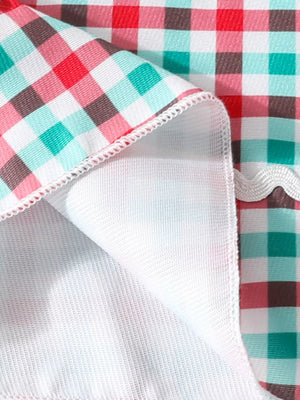 Festive plaid dress detail with red, teal, pink, and brown checks and white trim.