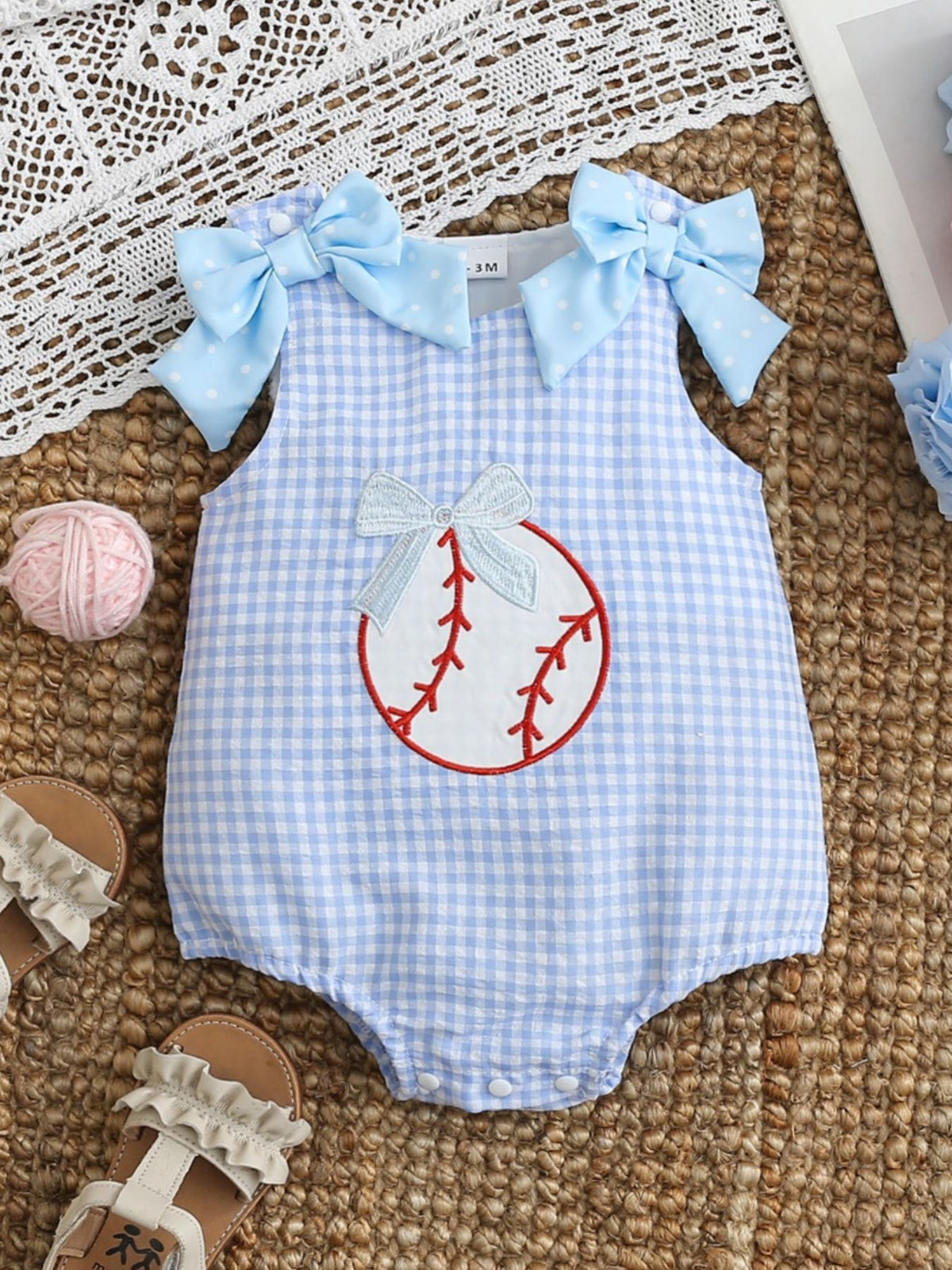 Baby one-piece in pastel blue gingham with baseball embroidery and bow details