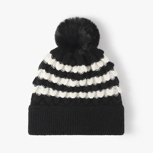 Black and white striped knit beanie with scalloped detail and black pompom.