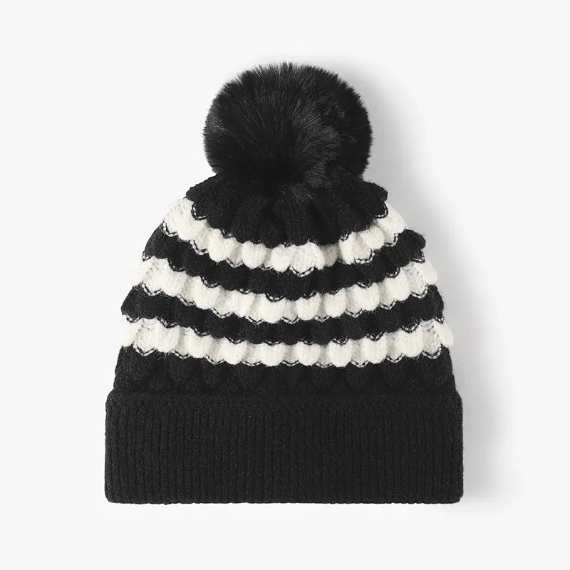 Black and white striped knit beanie with scalloped detail and black pompom.