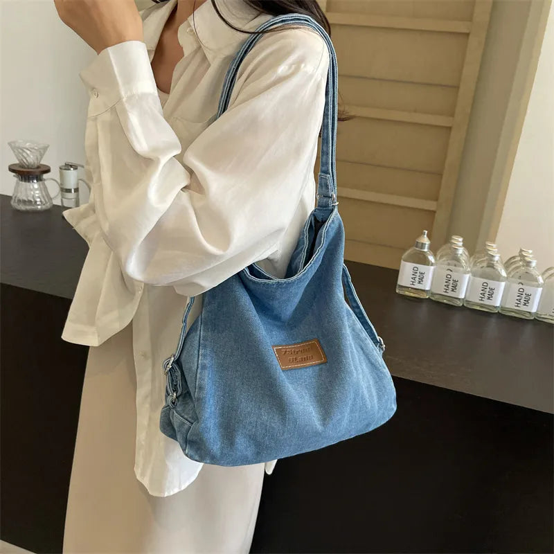 Medium denim hobo bag with leatherette patch and adjustable strap.