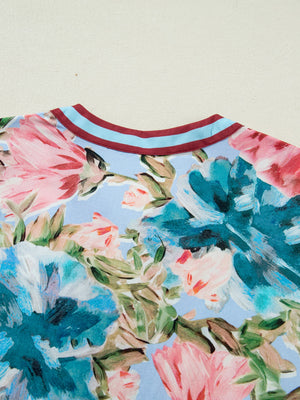 Women's cotton V-neck blouse with a bold floral print and striped trim neckline.